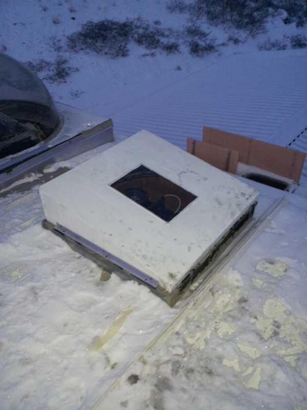 snowy roof with camera lens poking through opening.